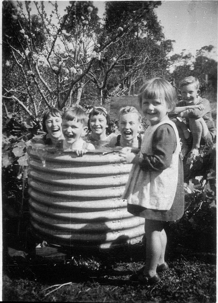 Children playing outside in a corrugated iron garden bed.