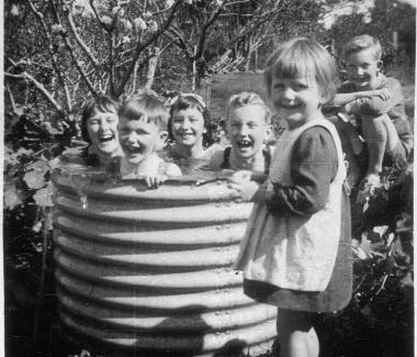 Children playing outside in a corrugated iron garden bed.