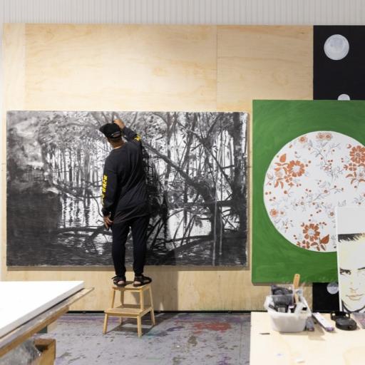 Daniel Boyd in his Marrickville studio, from behind, in front of a canvas