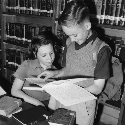 Two children reading book in front of bookcase