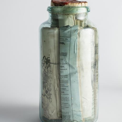 A glass bottle with documents folded inside.