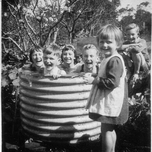 Children playing outside in a corrugated iron garden bed.